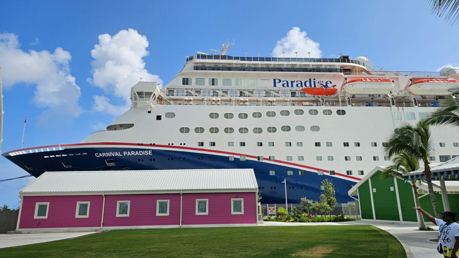 Carnival Paradise cruise ship docked near colorful buildings