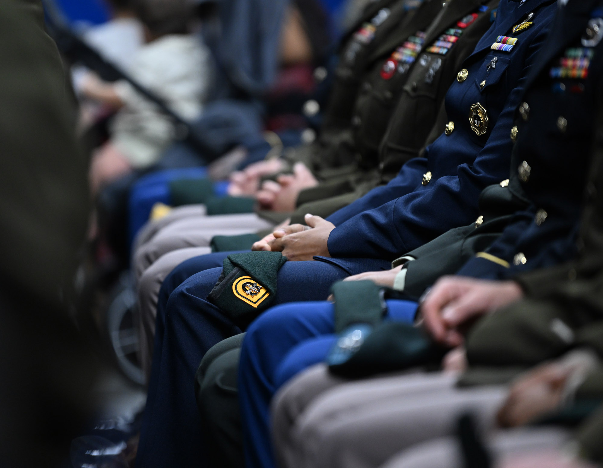 Military personnel seated, wearing uniforms and badges.