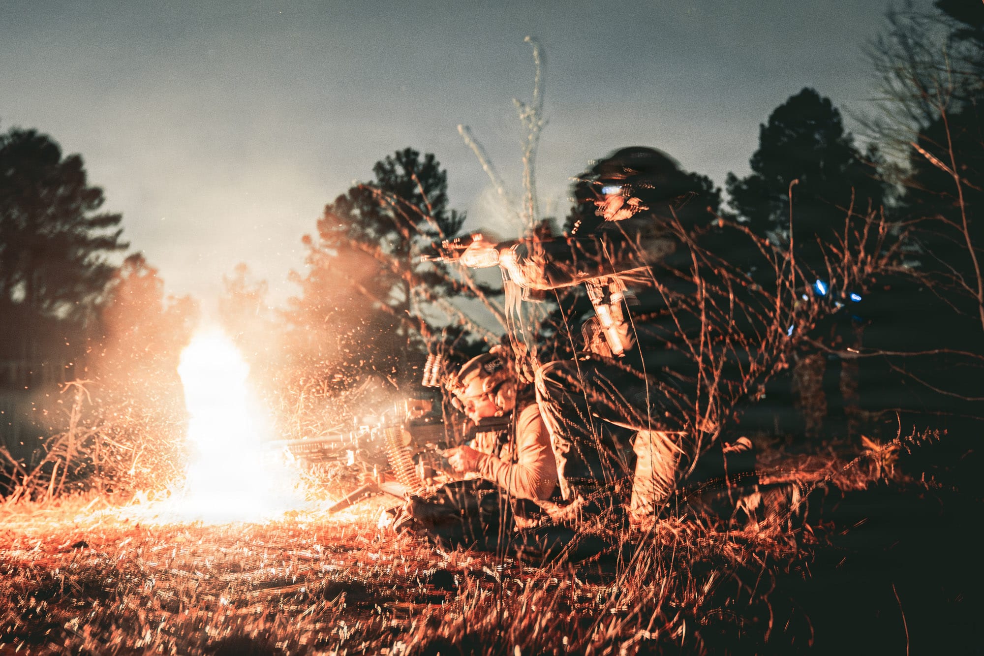 Soldiers around a campfire in a forest at night.