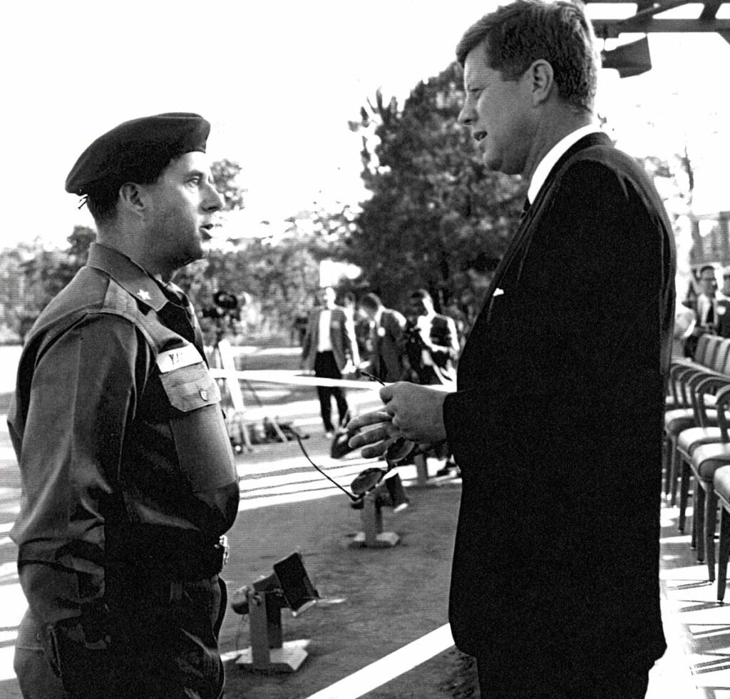 Man in military uniform talking to man in suit.