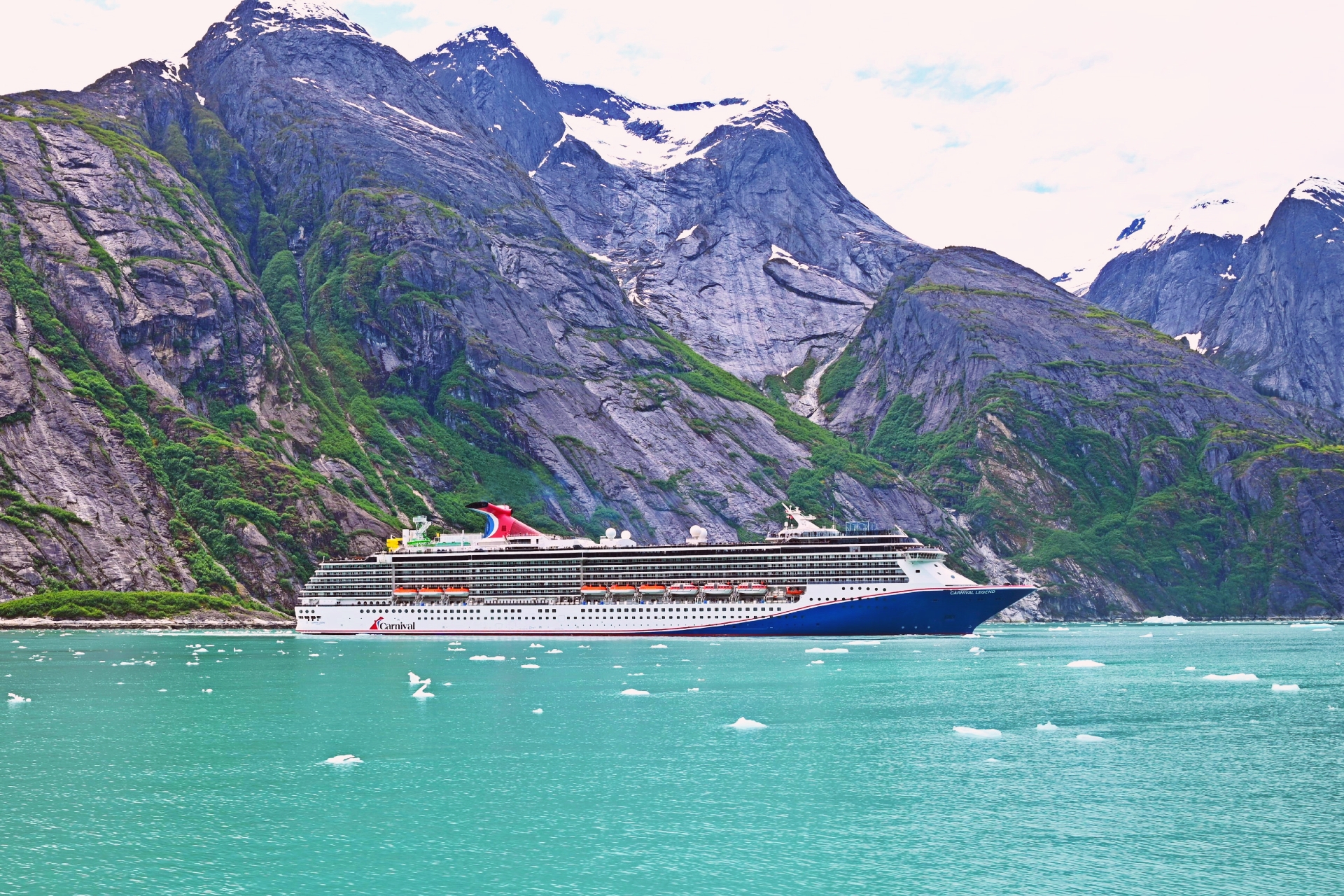 Cruise ship sailing through turquoise glacial fjord mountains