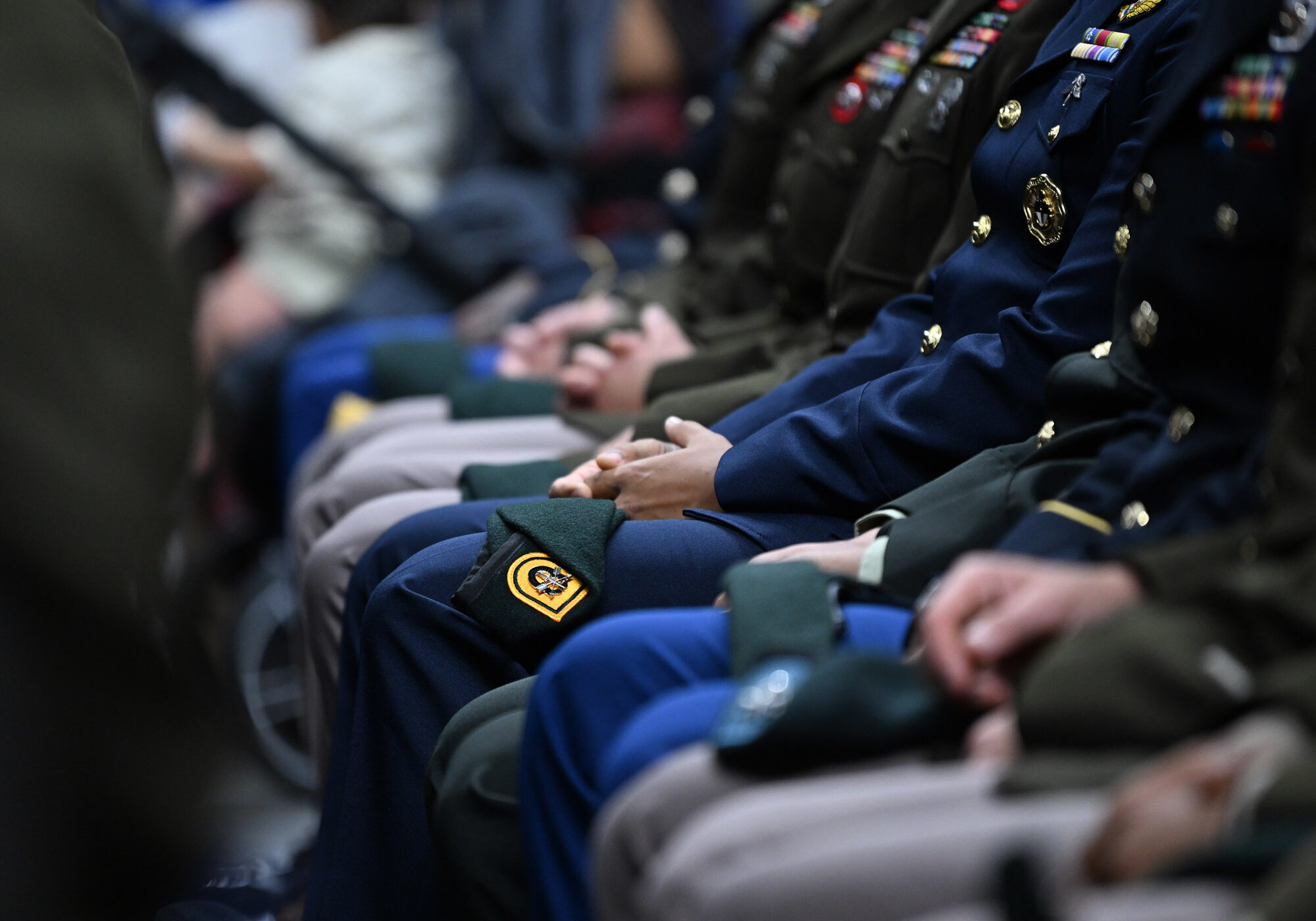 Military personnel seated, wearing uniforms and badges.