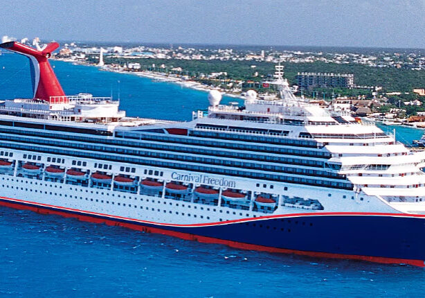 Cruise ship docked at Caribbean port, blue ocean view.